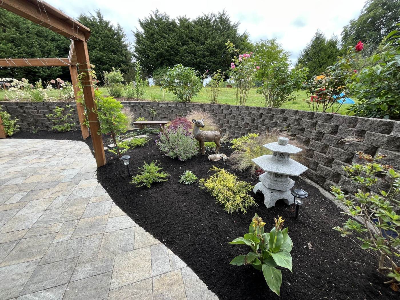 Mulch bed refresh along a wood fence